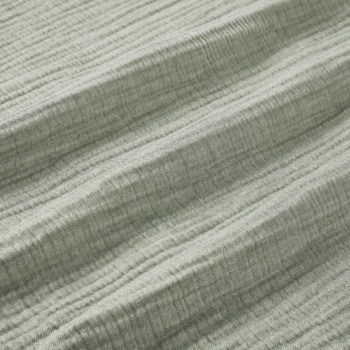BL-864-9496_9|Detailed close-up of a soft sage green textured blanket, highlighting its cozy crinkled fabric and natural fibers.