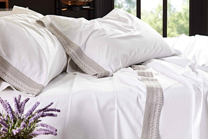 CSS-501-7284_4|Close-up of crisp white 100% cotton sheets and pillowcases with elegant woven grey trim, for a comfortable bed.