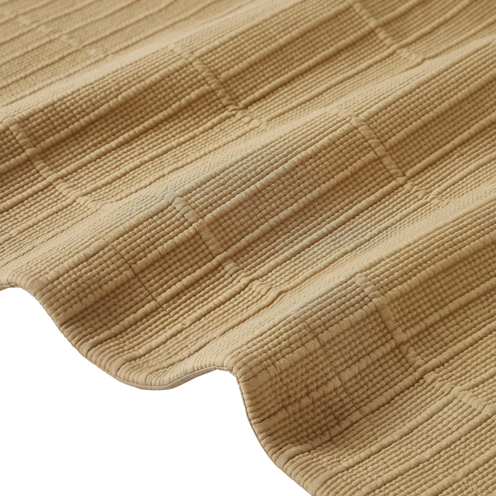 CL-269-9496_11|Close-up of a tan textured coverlet, highlighting its detailed weave and soft, ripple-like pattern. Luxurious bedding fabric.