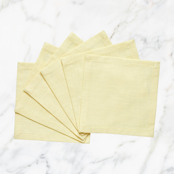 CNP-4907-66_1|Elegant set of light yellow linen fabric dinner napkins, fanned on a luxurious white marble background, perfect for entertaining.