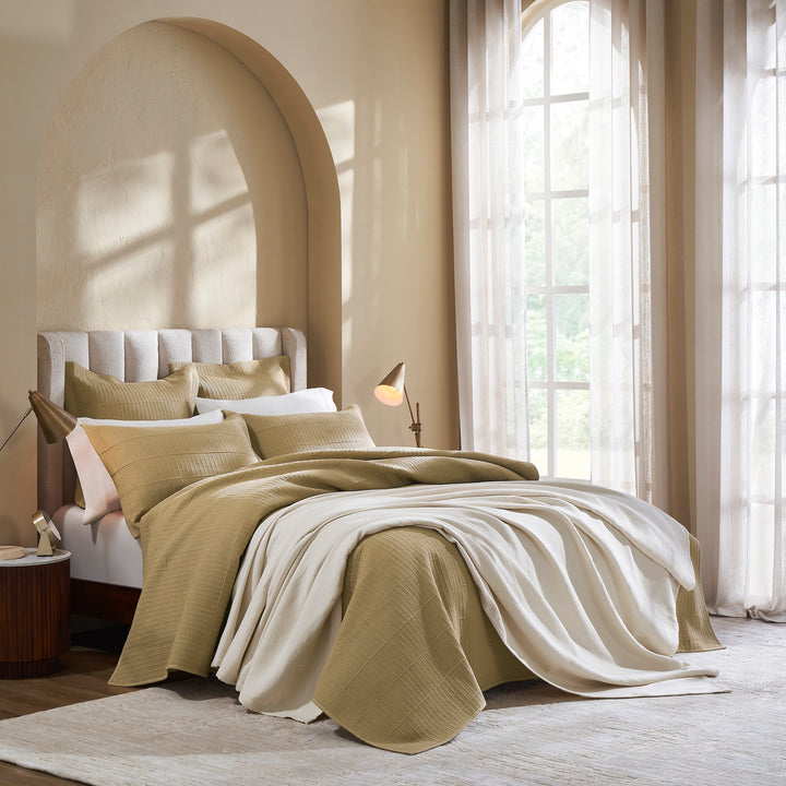 CL-269-9496_5|Elegant tan ribbed coverlet adorning a stylish bedroom bed, partially draped with a soft white throw, enhancing a warm aesthetic.