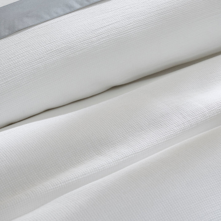 DT-067-9092_7|Close-up of a white textured duvet cover, elegantly folded with a subtle grey accent, emphasizing luxurious, soft fabric.