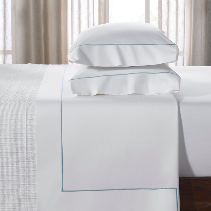 TFL-530-3980_3|Stacked pillows and folded white 100% cotton sheet with light blue piping, showcasing luxury hotel-style bedding.