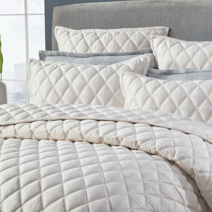 CL-180-9496_3|Close-up of cream diamond-quilted coverlet and pillows, highlighting soft texture and intricate stitching detail.