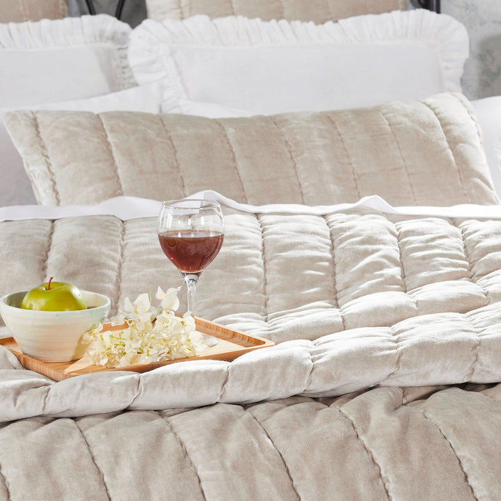 QT-339-9496_3|Close-up of a soft champagne velvet channel-quilted quilt, showcasing its luxurious texture on a bed.