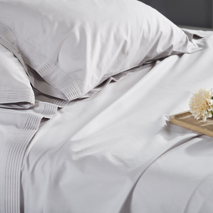 CSS-523-7284_3|Close-up of smooth light grey 100% cotton sheets on a bed, showcasing the soft texture and inviting pure cotton fabric.