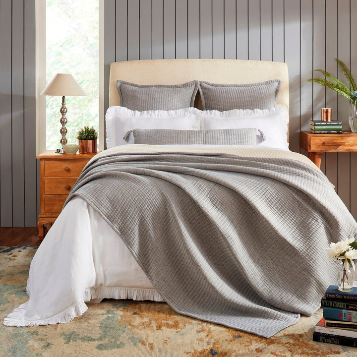 BT-108-9496_1|Stylish grey textured reversible quilt blanket elegantly draped over a bed with white sheets, enhancing modern bedroom decor.