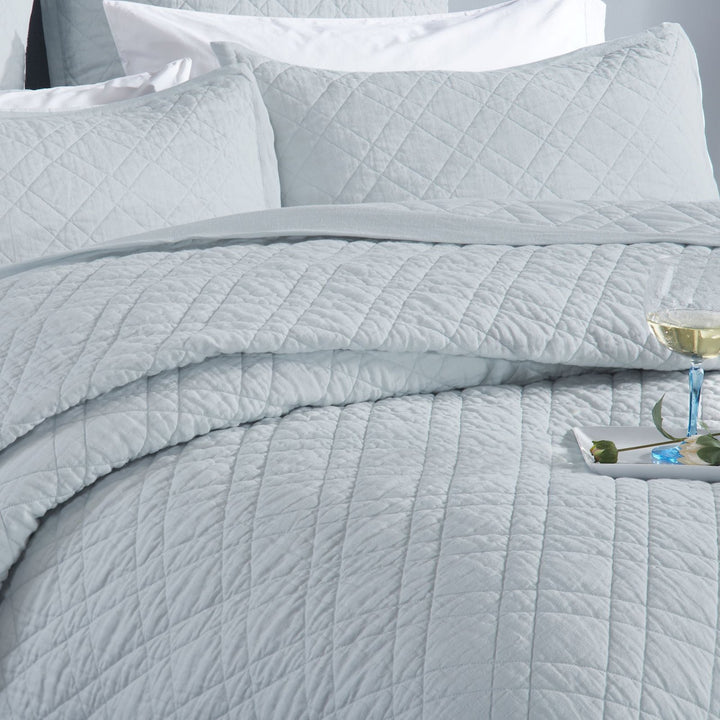 CL-255-11096_4|Elegant light blue quilted coverlet on a bed with matching pillows and a drink. Creates a serene and luxurious retreat.