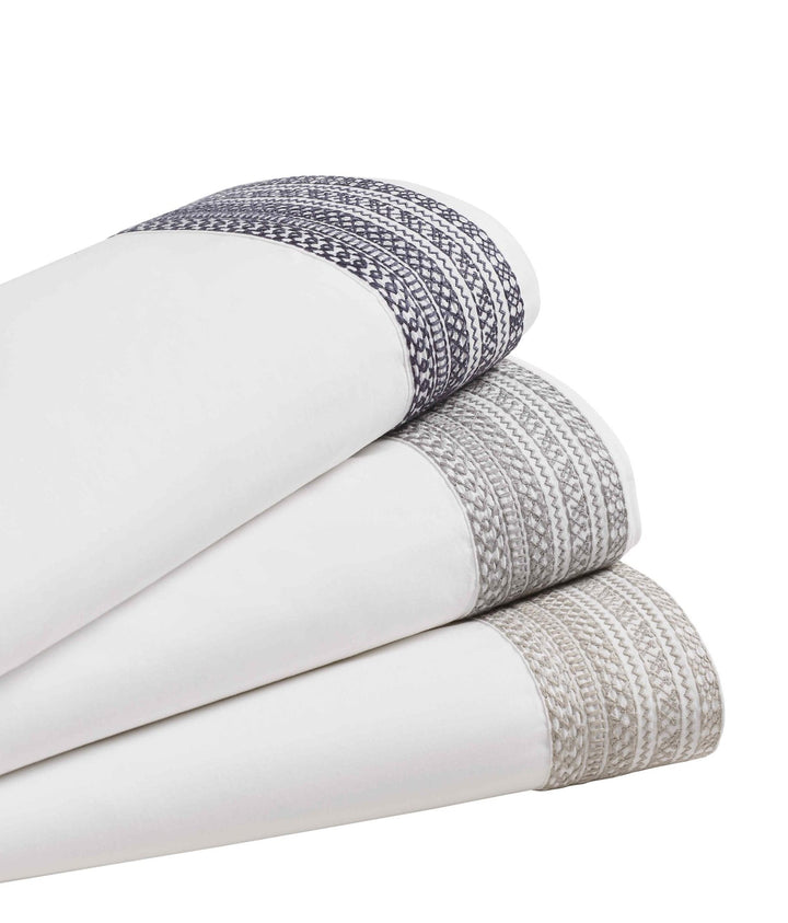 CSS-503-7284_2|Stack of folded 100% cotton sheets, showcasing elegant geometric embroidery in dark blue, gray, and taupe tones.
