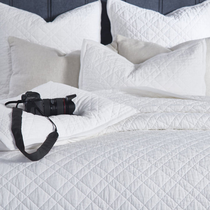 CL-253-11096_4|Intimate close-up of a crisp white quilted coverlet, emphasizing its soft, intricate texture for luxurious bedroom bedding.