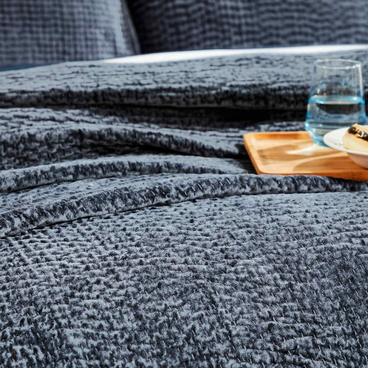CL-195-11096_4|Detailed view of a navy blue textured quilted coverlet on a bed, showcasing its soft plush fabric and contemporary design.