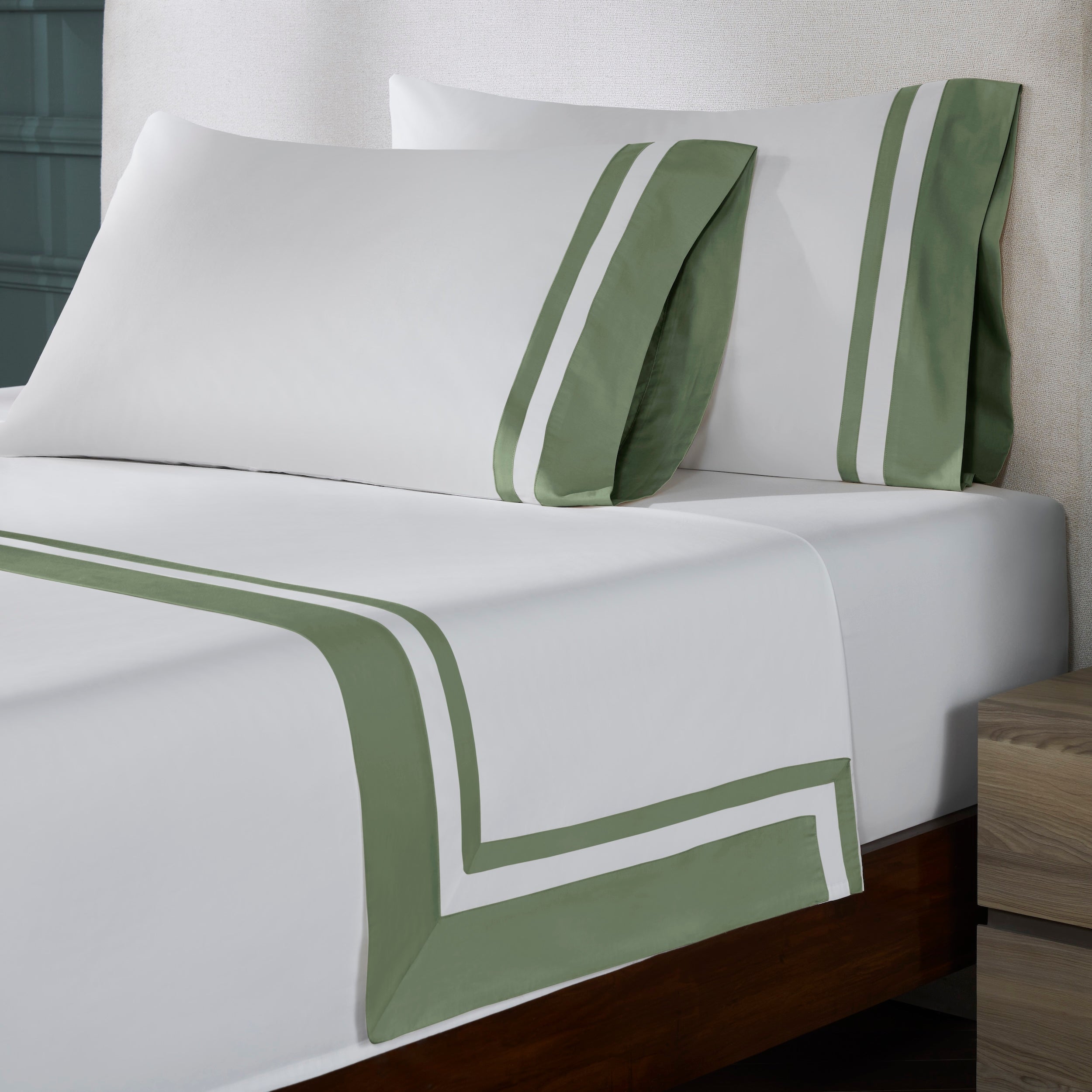 QFL-542-6080_2|Close-up of luxurious 100% cotton sheets on bed, crisp white fabric with stylish green borders & matching pillowcases.