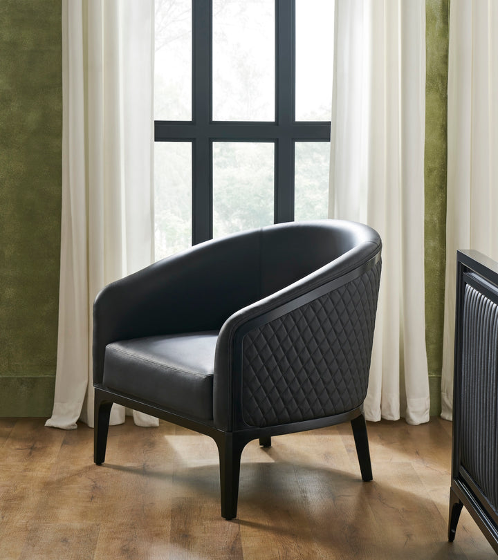 FN-5205-343329_1|Black leather armchair with quilted side panel and dark wood frame in a room with green walls, luxury furniture.
