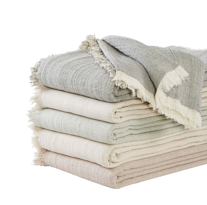 BT-112-9496_3|Stack of cozy fringed gauze throw blankets in assorted neutral tones, perfect for adding texture and warmth to any home.