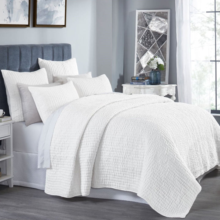 QT-358-9496_2|Crisp white quilted bedding set with subtle textured stripes, draped on a stylish bed creating a serene bedroom environment.