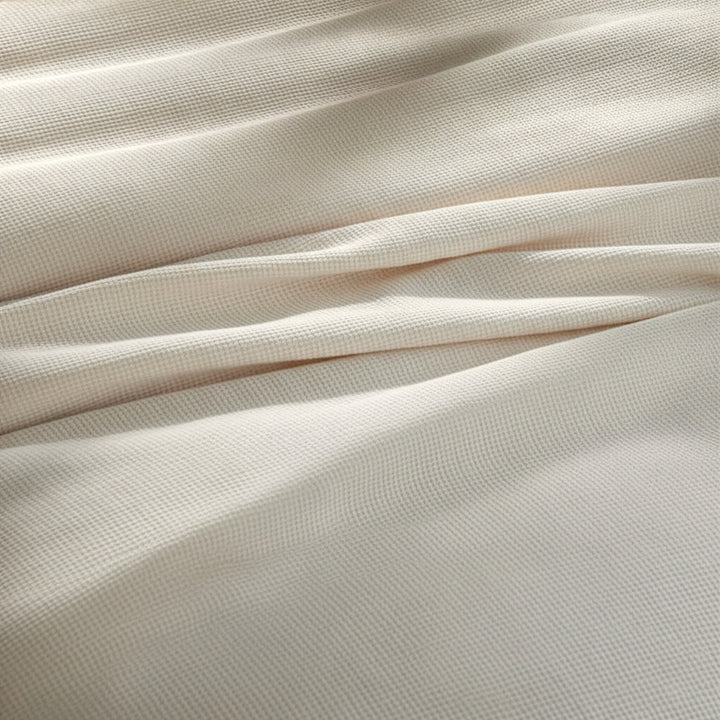 BL-860-11096_5|Close-up of a luxurious cream waffle weave blanket fabric, showcasing its intricate, soft texture and cozy feel. High-quality.
