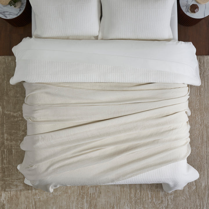BL-862-9496_4|Overhead view of a light beige cotton blanket folded neatly on a bed, showcasing its soft texture and cozy appeal.