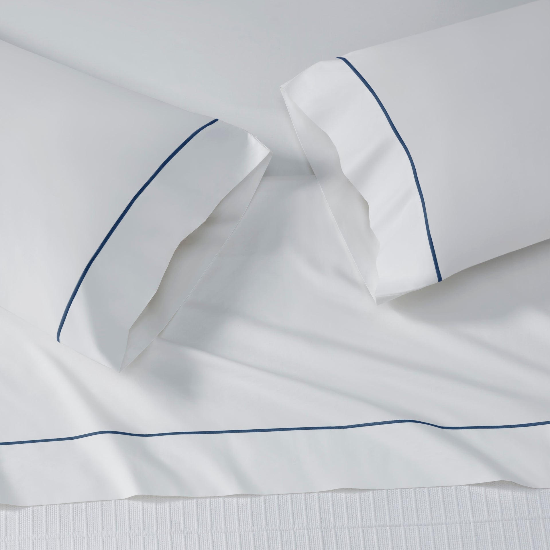 ASP-549-X_2|White 100% cotton flat sheet with a horizontal navy blue decorative border. Two white 100% cotton pillowcases with navy piping.