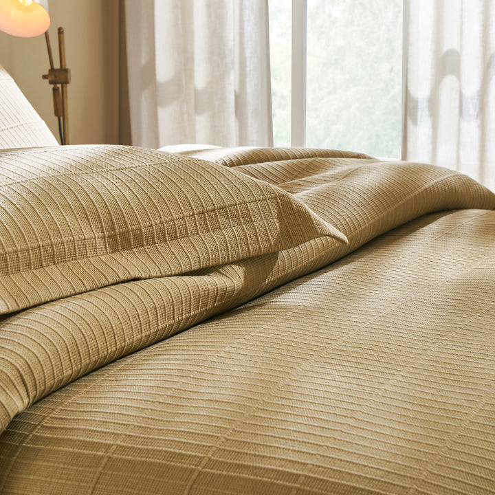 CL-269-11096_7|Close-up of a soft beige quilted coverlet on a bed, showcasing intricate texture and inviting comfort for a stylish bedroom.