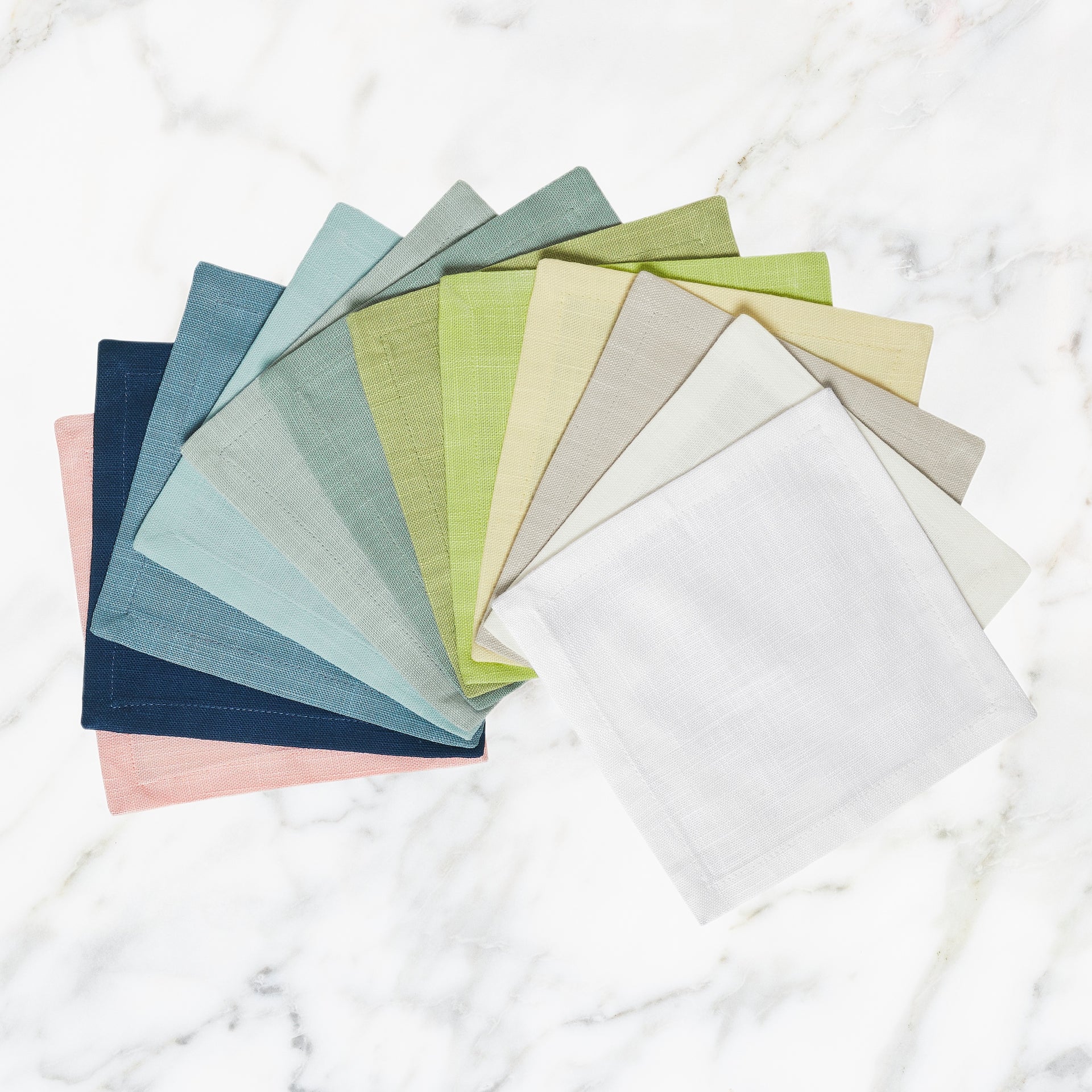 SWT-4913-66_1|A vibrant collection of linen fabric swatches fanned out on a marble surface, showcasing various hues for home decor choices.