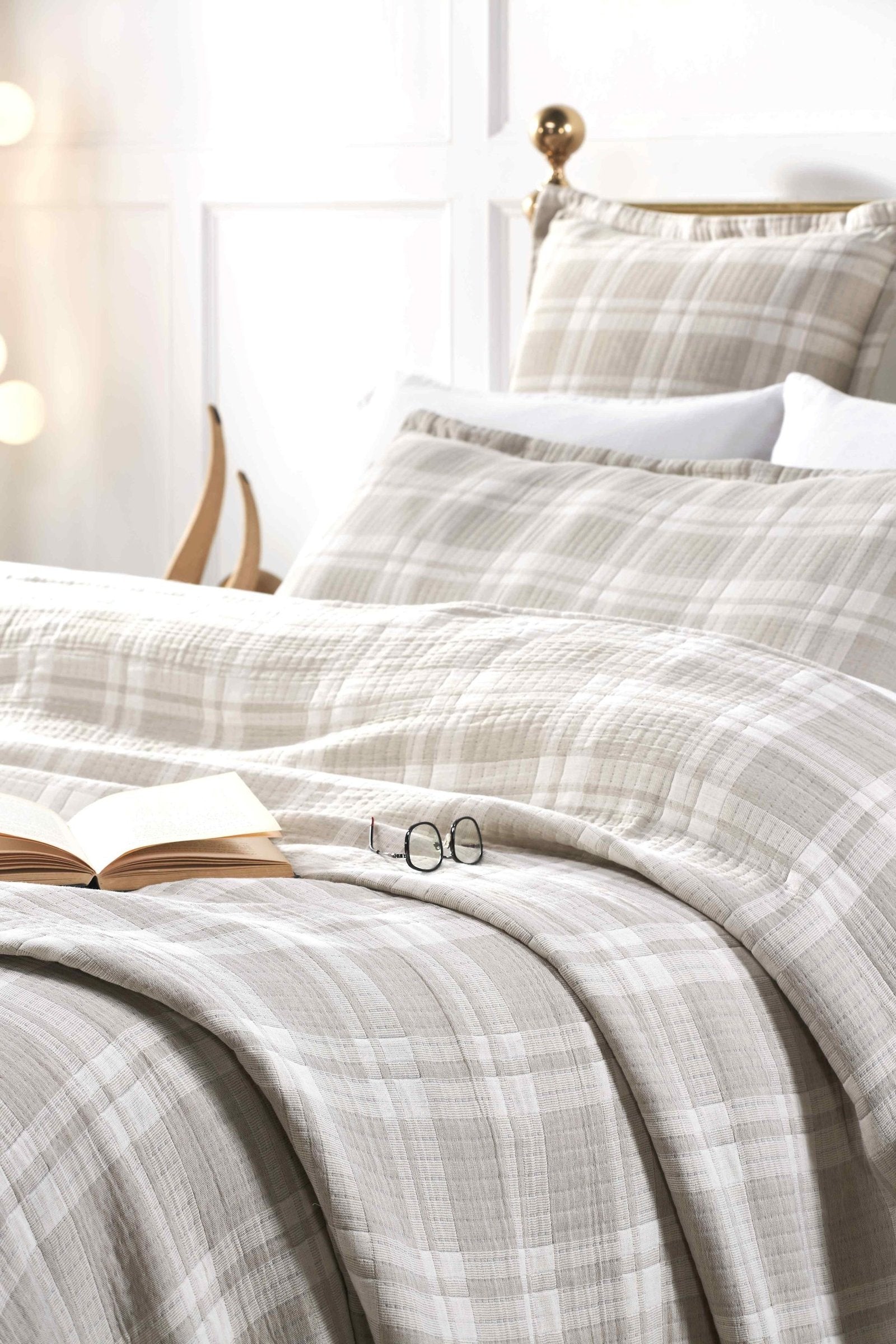 BT-120-11096_4|Cozy beige and white plaid quilted blanket draped on a bed with matching pillows, perfect for a relaxing evening.