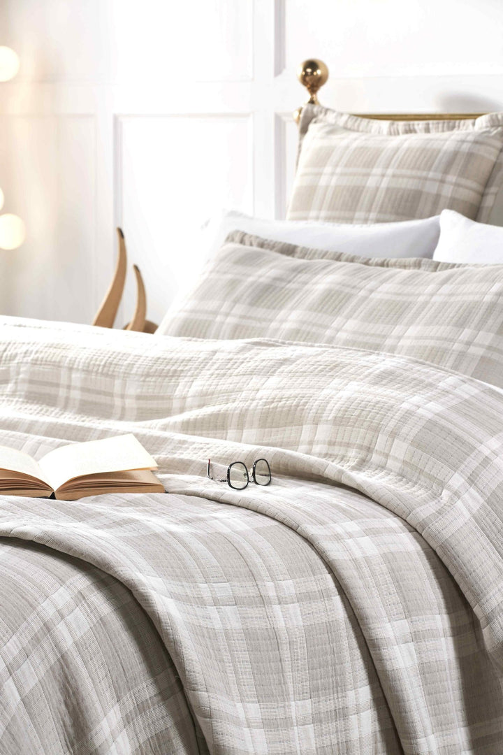 BT-120-11096_4|Cozy beige and white plaid quilted blanket draped on a bed with matching pillows, perfect for a relaxing evening.