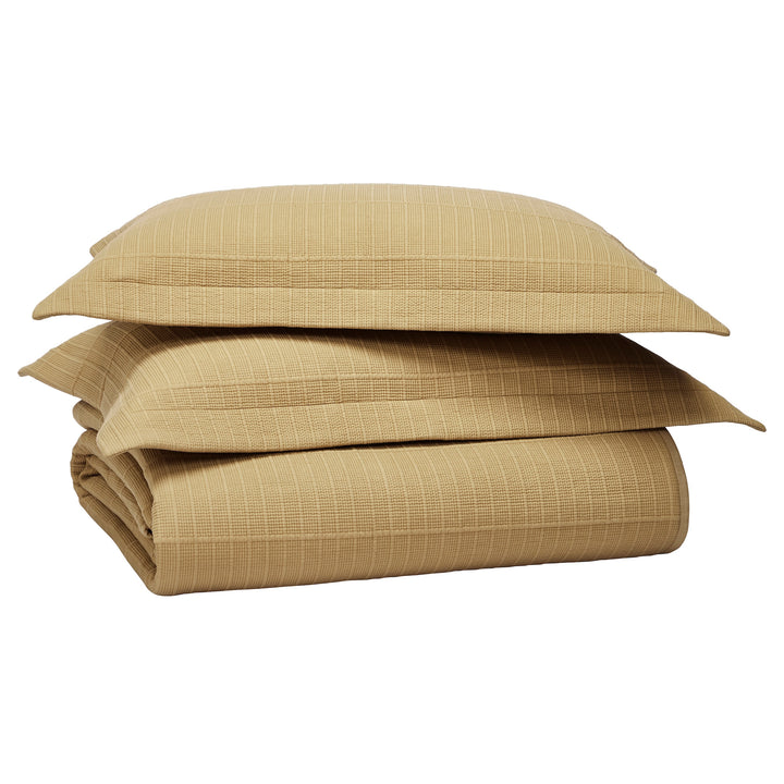 CL-269-9496_12|Stacked tan textured coverlet with two matching pillow shams, offering a complete and coordinated bedding set. Cozy comfort.