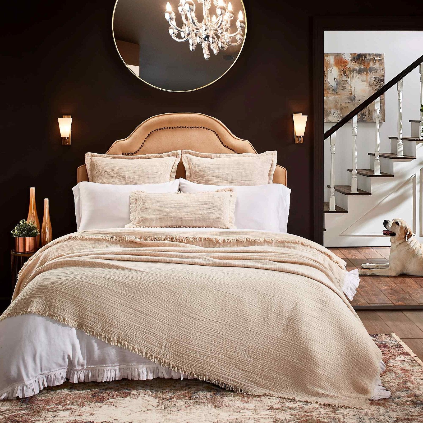 BT-115-9496_1|Cozy bedroom with a cream textured fringed blanket on a bed, upholstered headboard, and dog relaxing by stairs.