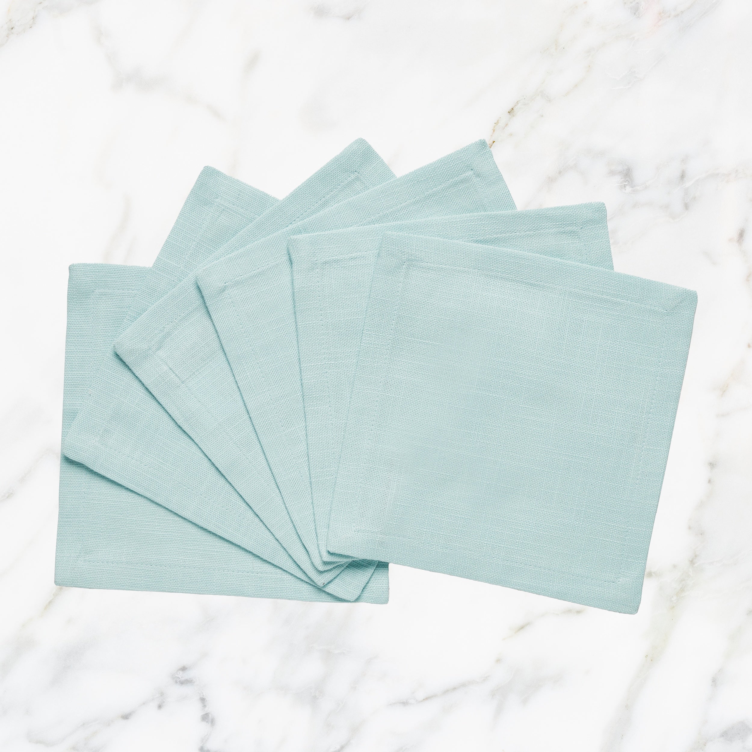 CNP-4903-66_1|Fanned set of elegant light blue linen napkins on white marble. Perfect for contemporary dining & sophisticated gatherings.