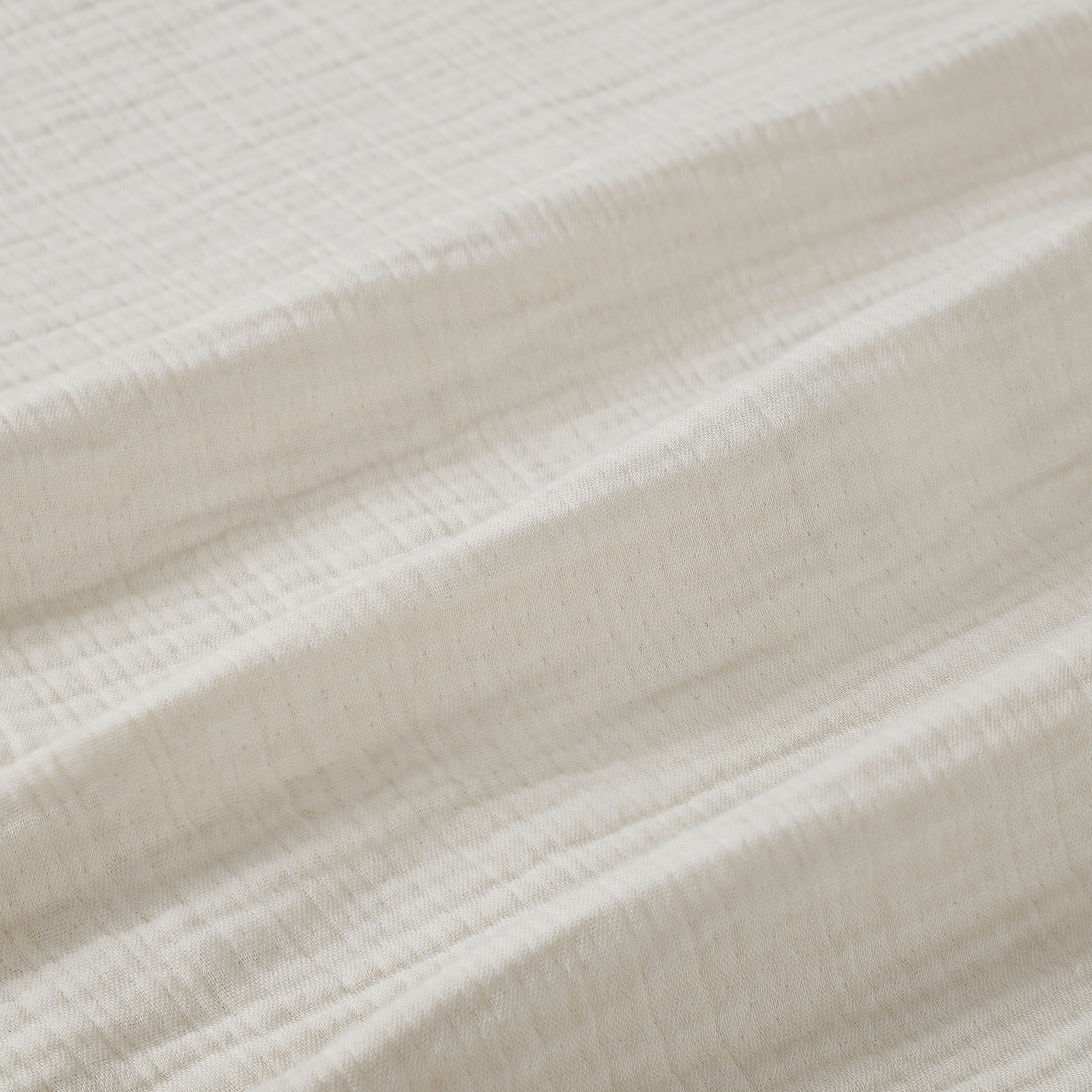 BL-862-9496_8|Close-up of a soft cream textured blanket, highlighting its breathable, natural cotton weave and cozy, inviting feel.