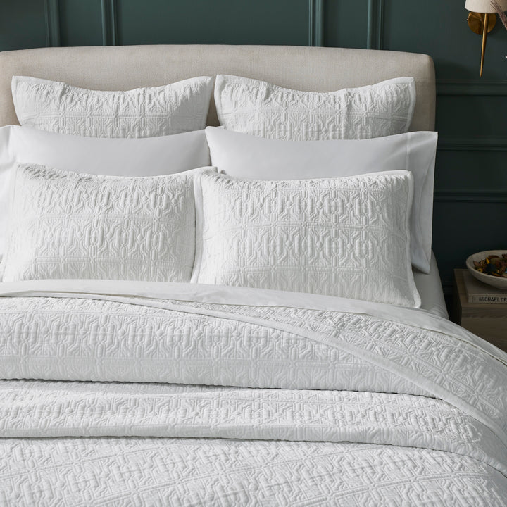 QT-376-11096_3|Close-up of a detailed white patterned quilt and matching shams, highlighting intricate texture and elegant bedroom design.