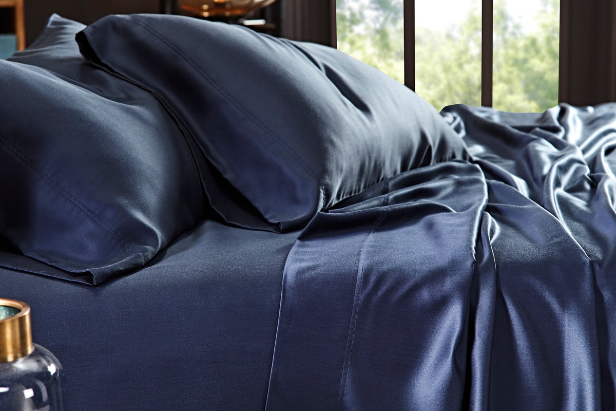 CSS-511-7284_3|Close-up of navy 100% Lyocell sheet set on bed. Visible flat sheet and pillowcases with sateen weave.
