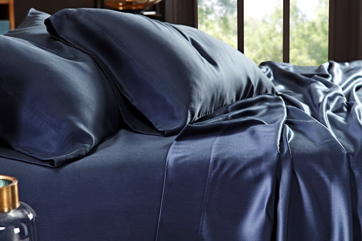 CSS-511-7284_3|Close-up of navy 100% Lyocell sheet set on bed. Visible flat sheet and pillowcases with sateen weave.
