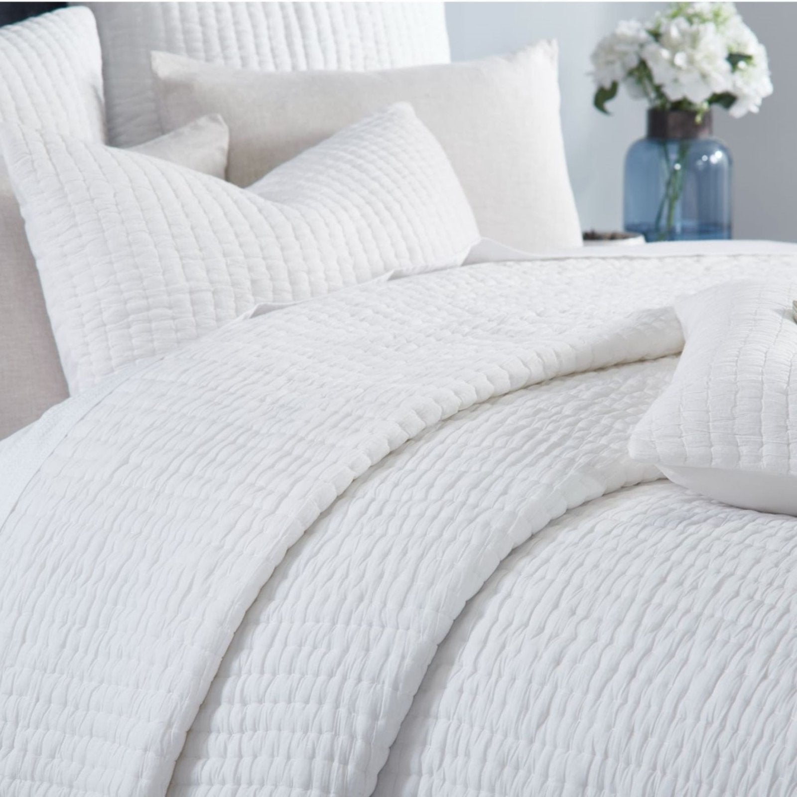 QT-359-9496-LOT1_4|Close-up of a soft white quilted cotton bedspread, showcasing its subtle textured pattern and cozy, inviting appeal.